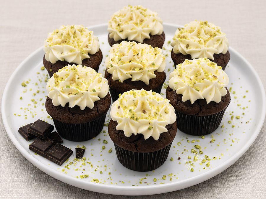Chocolate muffins topped with cream cheese frosting and crushed pistachio