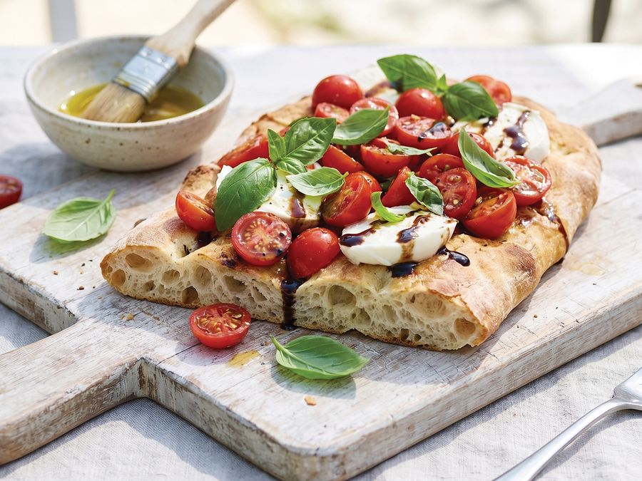 Pinsa topped with cherry tomatoes, mozzarella, basil and balsamic